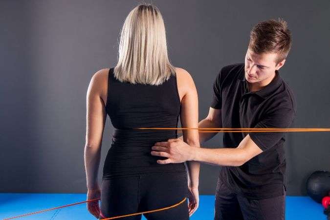 chiropractor adjusting the posture and discussing cost with female patient