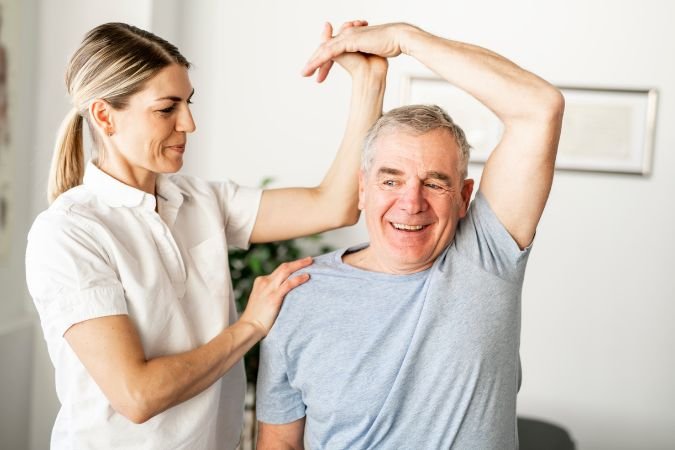 chiropractors work on shoulders of old man